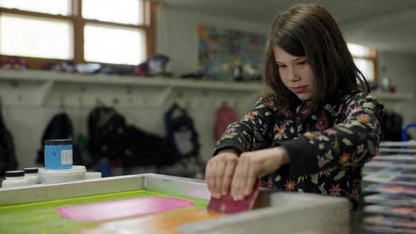 Une élève crée un zine avec une presse à sérigraphie.